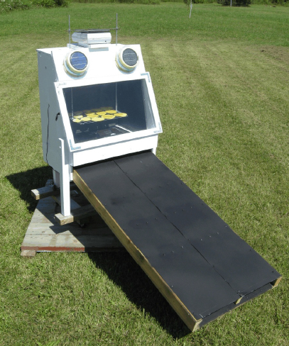 A small prototype solar dryer being used for research purposes. The large flat black surface is the heat collector.